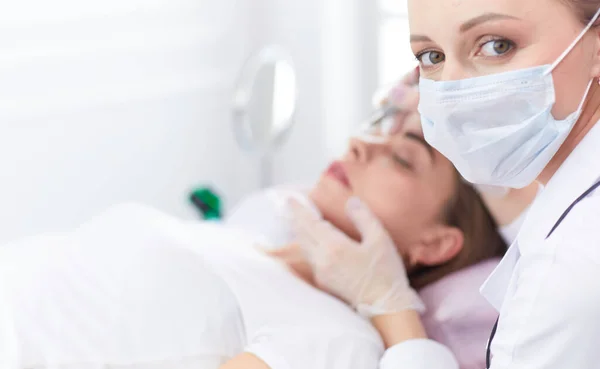 Young woman undergoing procedure of eyebrow permanent makeup in beauty salon — Stock Photo, Image