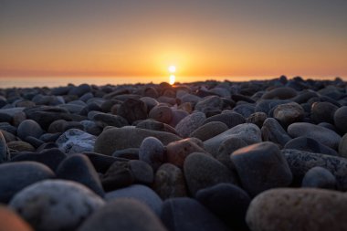 Akşam güneşi taş sahili aydınlatıyor.