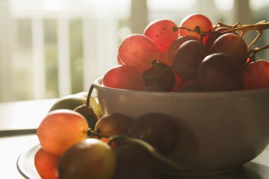 Bir demet kırmızı üzüm ve yeşil armut kasede, yakın çekim manzarası 