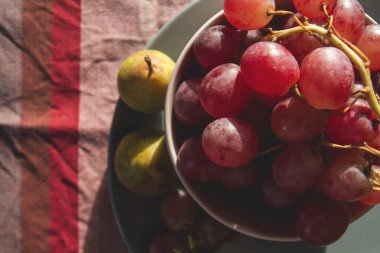 Bir demet kırmızı üzüm ve yeşil armut kasede, yakın çekim manzarası 