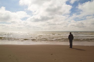 Yazın sonunda deniz kenarında tek başına duran bir adam. 