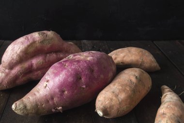 Koyu kırsal zeminde kırmızı renkte çiğ patates.