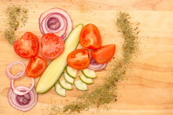 Tomatoes with cucumbers and red onions on a cutting board. Ripe cucumber and tomatoes with spices. Photo of vegetables for the cafe menu. Spices, onions, tomatoes, cucumbers cut and beautifully laid out