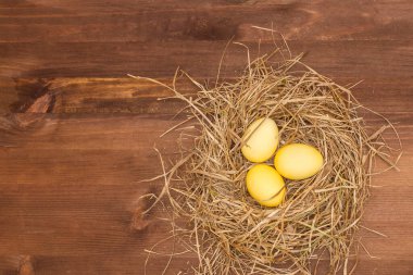 Paskalya, Paskalya yumurtası koleksiyonu. Kahverengi ahşap bir masada paskalya yumurtaları. Paskalya yumurtası ve saman. Yuvadaki sarı yumurtalar.