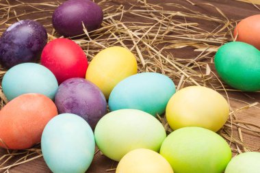  Sarı, yeşil, turuncu, biyuzovye ve uzay yumurtaları samanlıkta yatar. Paskalya yumurtası ve saman koleksiyonu. Arka arkaya çok renkli yumurtalar. Kahverengi ahşap bir masada Paskalya yumurtaları.