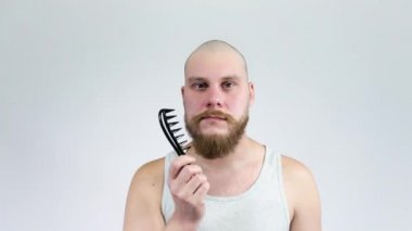 Genç adam kırmızı sakalını tarıyor. Büyük siyah tarak..