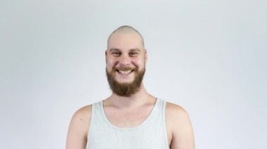 Sakallı kel bir adam, kameraya bakarak kahkaha atıyor.