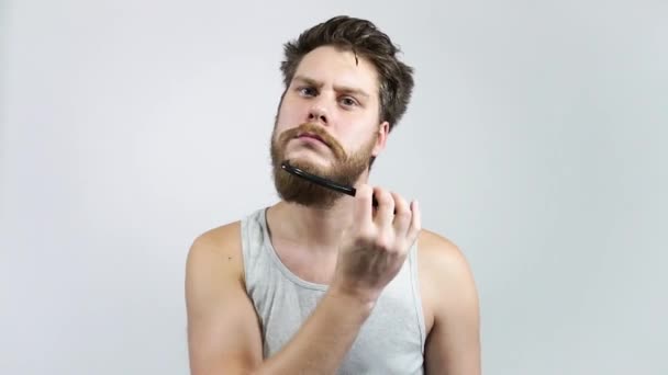 Un uomo che si pettina la barba. Hipster ragazzo Spazzolatura sua barba rossiccia . — Video Stock