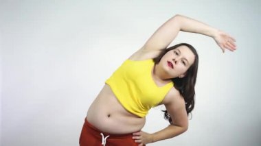 Kalın kafalı bir kız fitness ve güzel gülümsemelerle meşgul. Vücut pozitifliği.