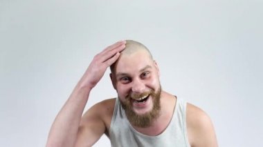 Genç kel adam kel kafasına dokundu ve güldü. Berber dükkanı.