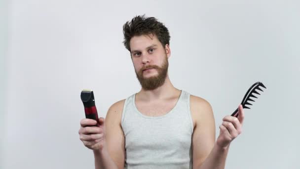 Welche Frisur sollte man wählen? Rasur oder nicht? Ein Mann mit Kamm und Haarschneidemaschine. — Stockvideo