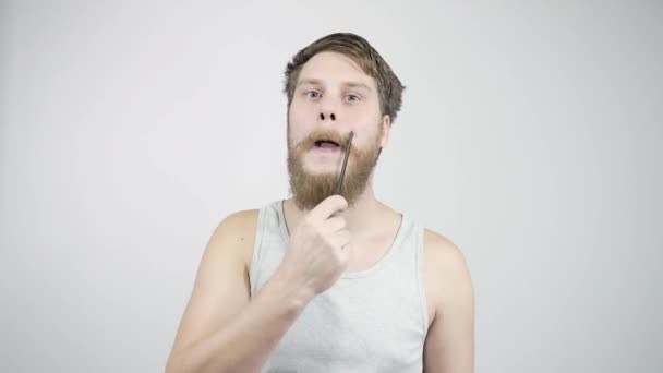 De man kamt zijn dikke baard uit kijkend in de spiegel. — Stockvideo