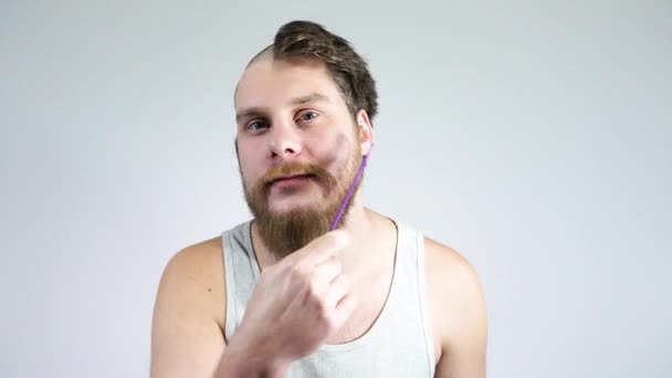 The guy combing his beard with a comb.Half shaved hair on his head. — Stock Video