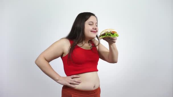 Overweight girl eating hamburger.Overeating fast food and obesity. — Stock Video
