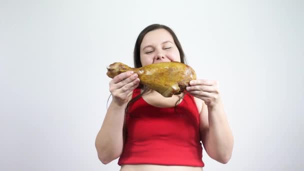 Mujer joven sosteniendo y comiendo una pierna frita de pavo. Grasa, obesidad, sobrepeso . — Vídeos de Stock