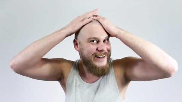 Bearded Guy raakt geschoren hoofd aan voor de spiegel en glimlacht. — Stockvideo