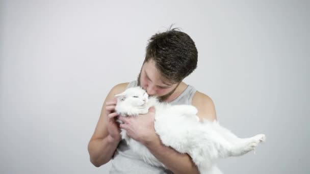 O tipo barbudo está a beijar o seu gato branco e fofo. Heterocromia — Vídeo de Stock