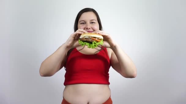 Schattig dik meisje overgewicht, maar eet de hamburger.Fast food en gezond voedsel. — Stockvideo