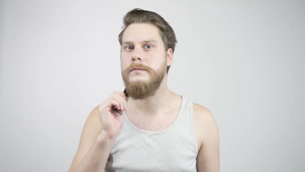 Un uomo con la barba pettina la barba guardandomi allo specchio . — Video Stock