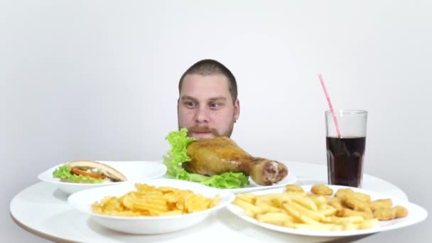 Guy mangia patatine fritte e altri fast food dal tavolo della casa . — Video Stock