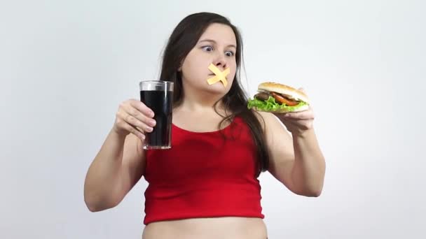 Jovem com fita adesiva sobre a boca, impedindo-a de comer junk food. — Vídeo de Stock