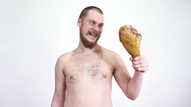 Un uomo sta con una coscia di pollo fritta e poi la mangia. . — Video Stock