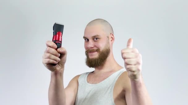 Kopasz fickó szakállal és ollóval a kezében, borotválja magát. Hüvelykujj fel. — Stock videók