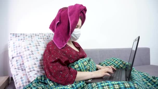 Девушка в медицинской маске работает с ноутбуком. Ковид 19. — стоковое видео