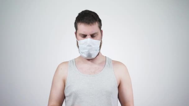Парень в медицинской маске болен, высморкается в носовой платок. — стоковое видео
