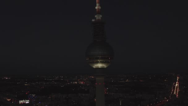 AERIAL: Close Up of Berlin Alemanha Torre de TV Alexanderplatz à noite com luzes da cidade tráfego — Vídeo de Stock