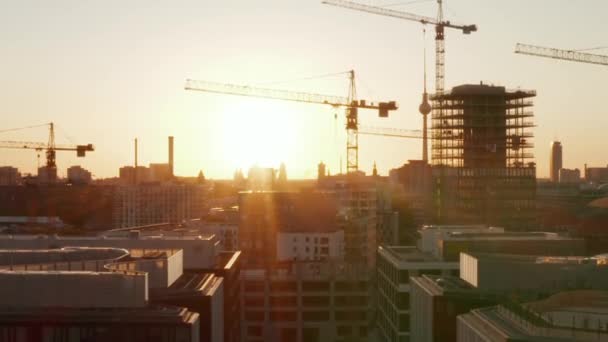 AERIAL: Berlin, Germany construction site with cranes with beautiful sunset, sunlight and view on Alexanderplatz TV Tower, Sunflairs — Stock Video