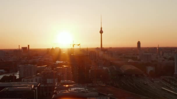 AERIAL:美しい夕日、日光でドイツのベルリン上空を飛行し、 Alexanderplatz TV TowerとOstbahnhofとMercedes Benz Arena 、 Sunflairsで見る — ストック動画