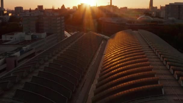 AERIAL: Vuelo sobre Berlín, Alemania Ostbahnhof Estación Central de Tren en la hermosa puesta del sol, la luz del sol y la vista sobre Alexanderplatz TV Tower, Sunflairs — Vídeo de stock