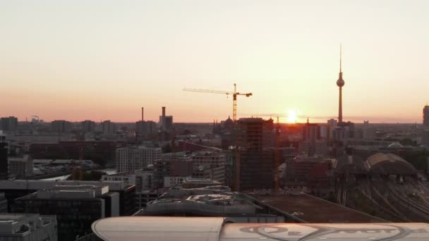 AERIAL: Lot nad Berlinem, Niemcy o pięknym zachodzie słońca, światło słoneczne i widok na wieżę telewizyjną Alexanderplatz i Ostbahnhof i Mercedes Benz Arena, Słoneczniki — Wideo stockowe