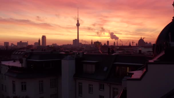 AERIAL: Vacker utsikt över Berlin TV Tower Alexanderplatz med rök på hustak vid soluppgången i rött morgonljus, vinter, storstad — Stockvideo