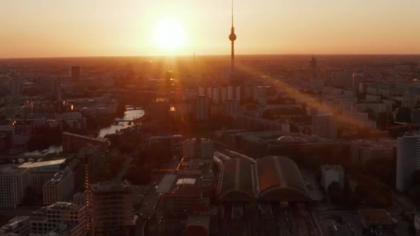 AERIAL: Vuelo sobre Berlín, Alemania en la hermosa puesta del sol, la luz del sol y la vista de Alexanderplatz TV Tower y Ostbahnhof, Sunflairs — Vídeo de stock