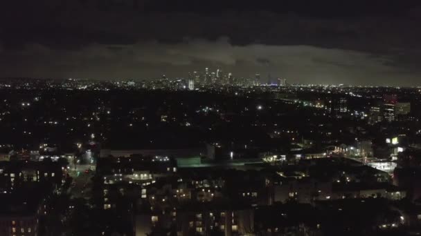 AERIAL: Nachts über dem dunklen Hollywood Los Angeles mit Wolken über der Innenstadt und den Lichtern der Stadt — Stockvideo