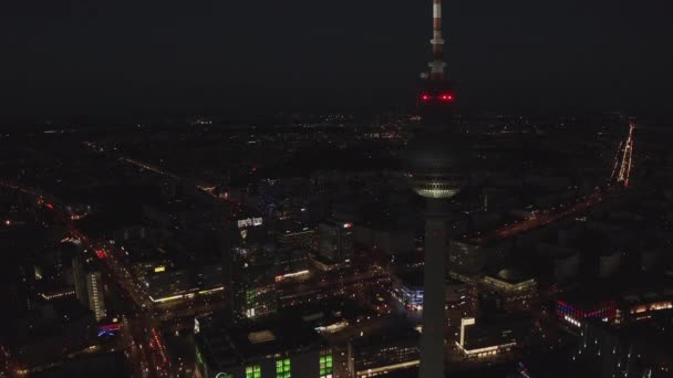 AERIAL: Close Up di Berlino Germania Torre della TV Alexanderplatz di notte con traffico di luci cittadine — Video Stock