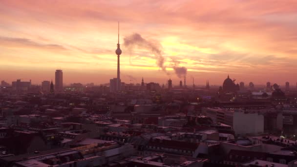 AERIAL: Bela vista da Torre de TV de Berlim Alexanderplatz com fumaça nos telhados ao nascer do sol em luz vermelha da manhã, inverno, cidade grande — Vídeo de Stock