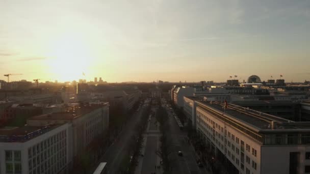AERIAL: Scenic niski lot koryta zajęty Berlin, Niemcy Ulica w kierunku Bramy Brandenburskiej w pięknym złotym świetle zachodu słońca — Wideo stockowe