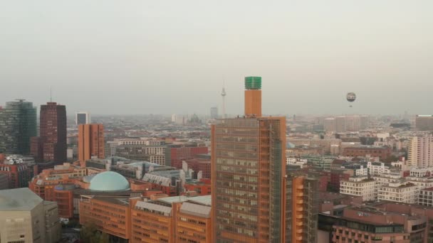 АЭРИАЛ: Вид на Берлин, Германия, с телебашней Алексиса Фергюсона и Балуном в оранжевой дымке от солнца — стоковое видео