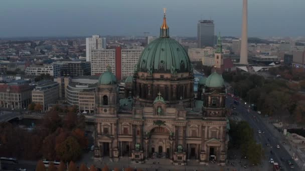 AERIAL: Kroužení Berlínské katedrály krásné staré struktury v pulzujících podzimních barvách se zlatým křížem na vrcholu a městský život pohybující se — Stock video