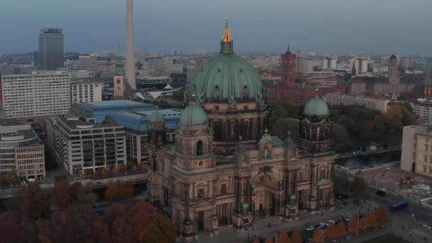 AERIAL: Kroužení Berlínské katedrály krásné staré struktury v pulzujících podzimních barvách se zlatým křížem na vrcholu a městský život pohybující se — Stock video