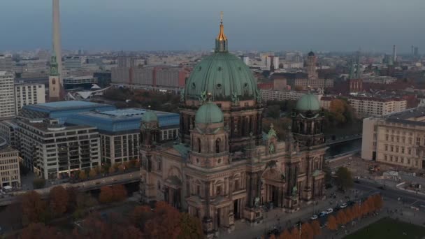 AERIAL: Kroužení Berlínské katedrály krásné staré struktury v pulzujících podzimních barvách se zlatým křížem na vrcholu a městský život pohybující se — Stock video