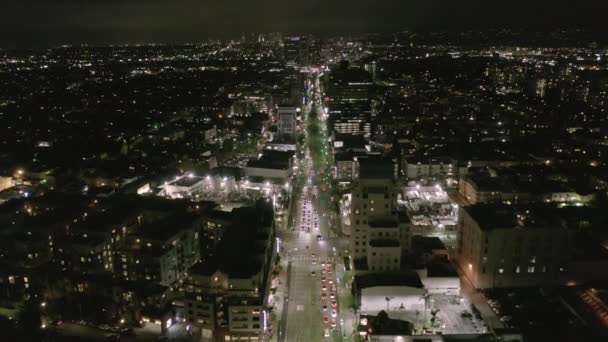 AERIAL: Voo sobre Wilshire Boulevard Street em Hollywood Los Angeles à noite com vista sobre ruas e luzes de trânsito da cidade — Vídeo de Stock