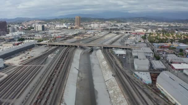 AERIAL: Río Los Ángeles con agua en el cielo nublado nublado junto a las vías de tren — Vídeos de Stock