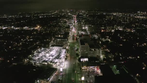 AERIAL: Vlucht over Wilshire Boulevard Street in Hollywood Los Angeles 's nachts met uitzicht op de straten en de stad Car Traffic Lights — Stockvideo