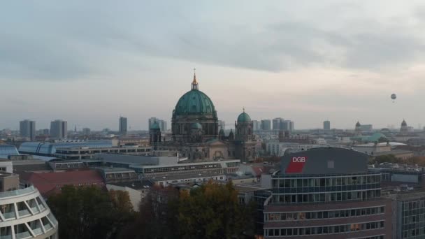 AERIAL: Sobre los tejados de Berlín, Alemania centro de la ciudad en los colores del otoño hacia la catedral de Berlín en la puesta del sol hermosa — Vídeo de stock
