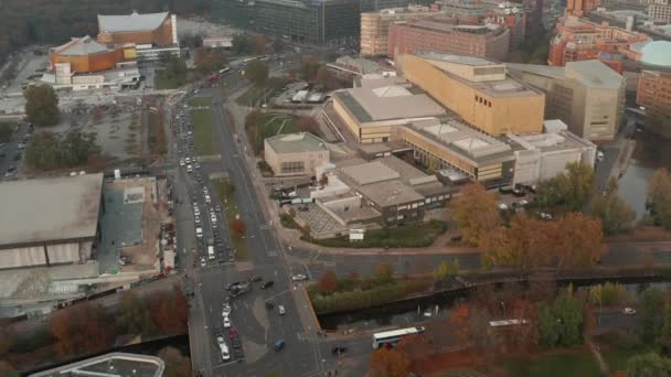 AERIAL: Vista del tráfico urbano típico alemán con transporte público de autobuses y transporte de coches en hermoso otoño naranja, ambiente invernal — Vídeos de Stock