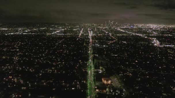AERIAL: Vista nocturna de Los Ángeles con Wilshire Boulevard Glowing Streets y semáforos de coches urbanos — Vídeos de Stock